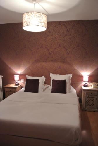 a bedroom with a large white bed with two lamps at Hotel Le Central in Boussac