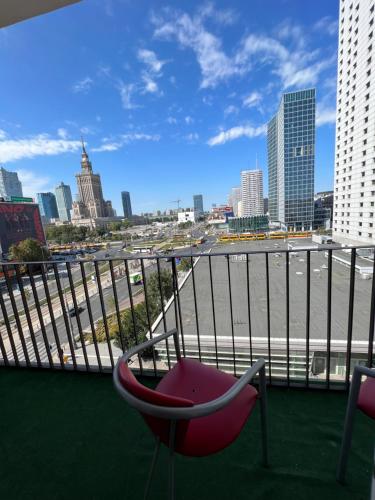 una sedia rossa su un balcone con vista sulla città di Marszałkowska Apartments Studio Central Warsaw a Varsavia