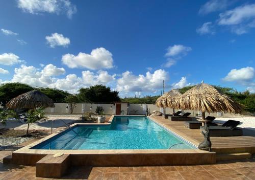 a swimming pool with two umbrellas and a resort at Pura Vida Aruba Appartement Palma in Noord
