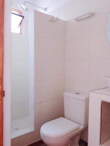 a white bathroom with a toilet and a shower at Casita de Piedra in Bogotá