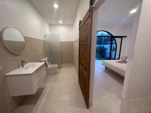 a bathroom with a sink and a toilet and a bed at Private pool villa in Thongsala