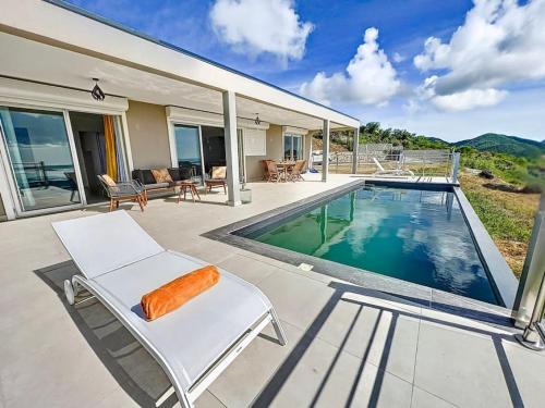 a house with a swimming pool and a white chair at Villa Grand Horizon with extraordinary 180 degree sea view in Saint Martin