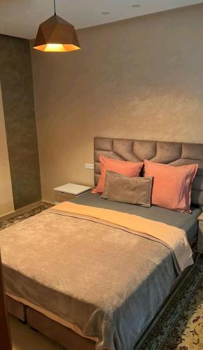 een slaapkamer met een groot bed met oranje kussens bij Super appartement in Aïn ej Jmel