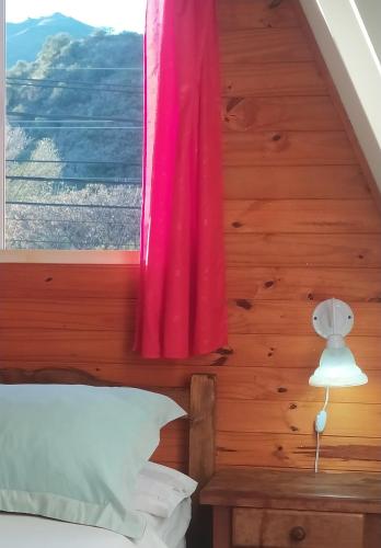 a bedroom with a window with a pink curtain at Cabañas en Koslay Ñalala Ivoqué con piscina climatizada en épocas cálidas in Juana Koslay 