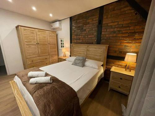 a bedroom with a large bed and a brick wall at Casa Enxaimel 02 em Pomerode in Pomerode