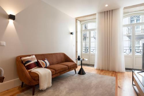 a living room with a brown couch and windows at Ando Living - Flores Townhouse in Porto