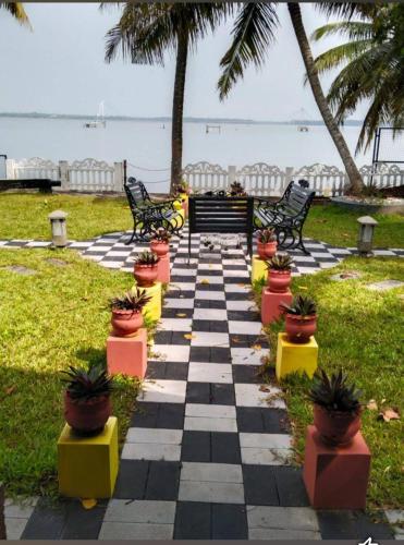 un tablero de ajedrez con macetas y bancos en la playa en Sambranikodi Resort and Home Stay, en Kollam