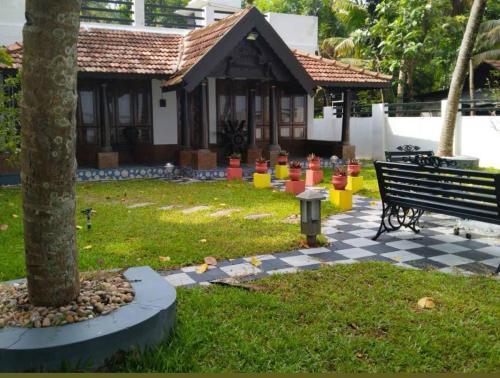 un parque con un banco y un árbol y un edificio en Sambranikodi Resort and Home Stay, en Kollam