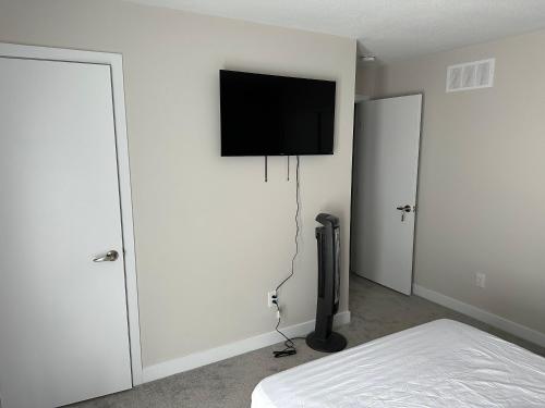 1 dormitorio con 1 cama y TV de pantalla plana en la pared en 2 bedroom ensuite, en Stittsville