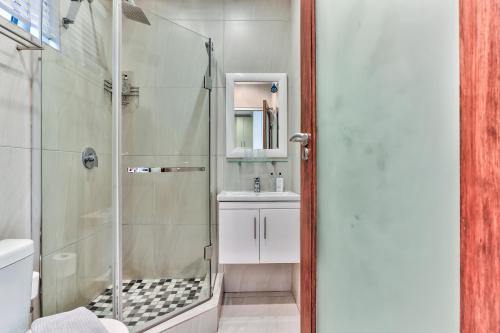 a bathroom with a glass shower and a sink at Fairmile on Main in Cape Town