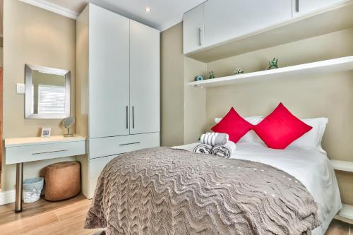 a bedroom with a large bed with red pillows at Fairmile on Main in Cape Town