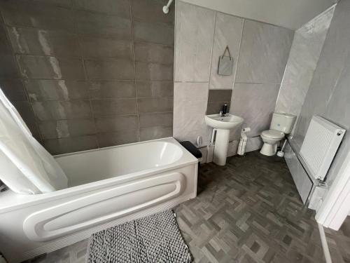a bathroom with a tub and a toilet and a sink at Elegant 3 Bedroom Apartment in Rowley Regis