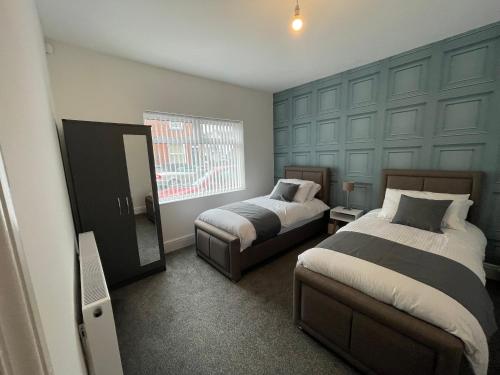 a bedroom with two beds and a mirror in it at Elegant 3 Bedroom Apartment in Rowley Regis