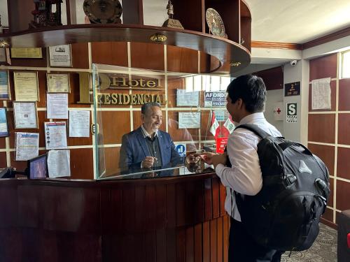 a man standing at a bar talking to a customer at Hotel Presidencial in Chiclayo