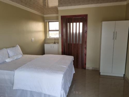 Un dormitorio con una gran cama blanca y una ventana en Airport Airbnb en Richards Bay