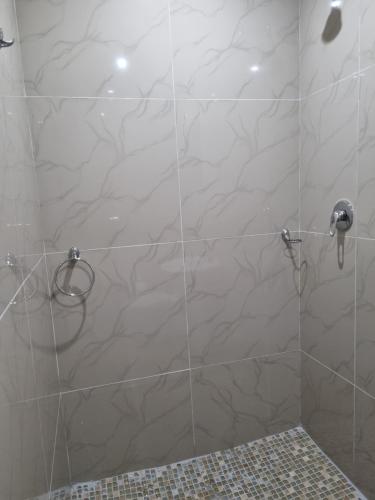 een douche met een glazen deur en een douchekop bij Airport Airbnb in Richards Bay