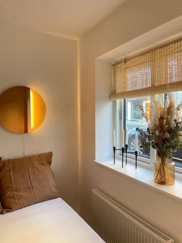 a bedroom with a bed and a window with a vase at Skandinavisk City-lejlighed! in Odense