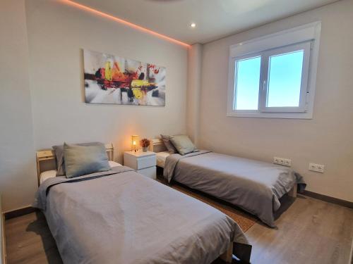 1 Schlafzimmer mit 2 Betten und einem Fenster in der Unterkunft Emerald Apartment - Spacious Modern 2 Bedroom in Benalmádena