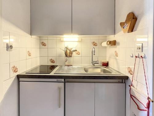a kitchen with white cabinets and a sink at Studio cosy skis aux pieds avec balcon et piscine chauffée - FR-1-267-205 in Le Corbier