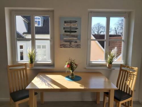 a dining room table with two chairs and two windows at Wohnung Sonnenschein Wolgast in Wolgast