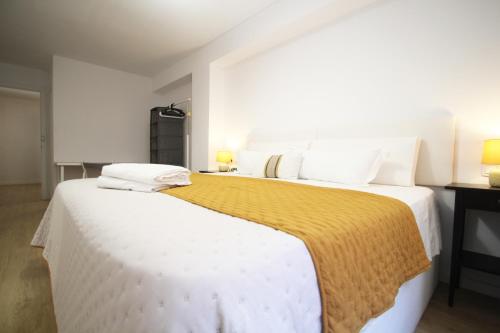a bedroom with two beds with white sheets and yellow blanket at Casa Ross in Valencia