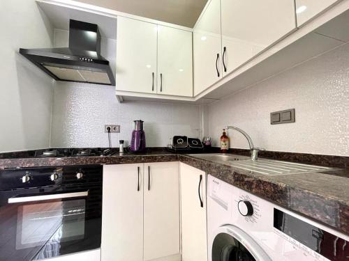 a kitchen with white cabinets and a washer and sink at Karavan tosbik in Lara