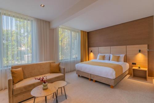 ein Hotelzimmer mit einem Bett und einem Sofa in der Unterkunft Hotel Osetia Garden in Momtschilgrad