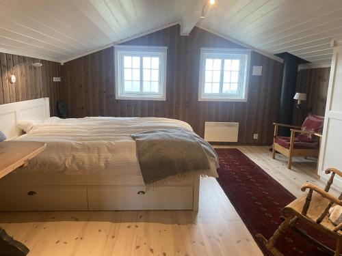 a bedroom with a bed and a table and windows at Solrik og flott hytte i Havsdalen in Geilo