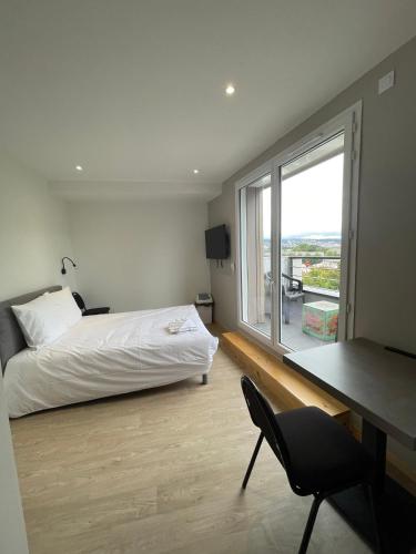 une chambre avec un lit, un bureau et une fenêtre dans l'établissement LE SALVADOR - Appart'Hôtel de 18m2 à 44m2, à La Talaudière