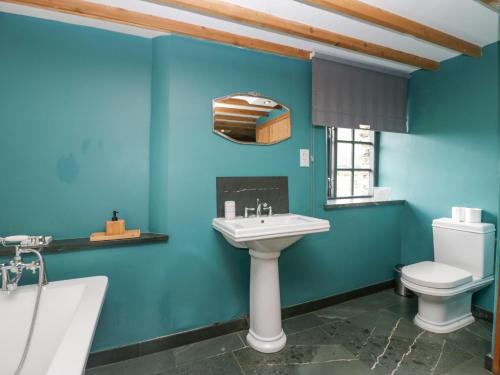 baño con paredes azules, lavabo y aseo en The Chapel, en Millom