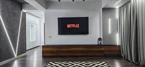 a living room with a television on a wall at Eclipsei ApartHotel in Popeşti-Leordeni