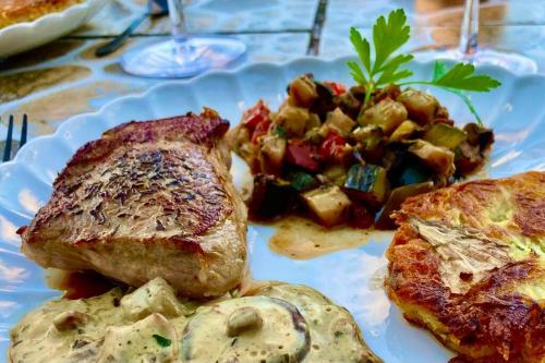 a plate of food with meat and vegetables on a table at L'insolite TAMIA in Asperjoc