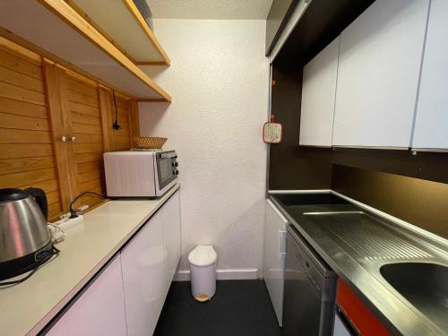 une petite cuisine avec un évier et un micro-ondes dans l'établissement Appartement 2P pour 4 pers., balcon sud, au pied des pistes, centre Les Menuires - FR-1-452-204, aux Menuires