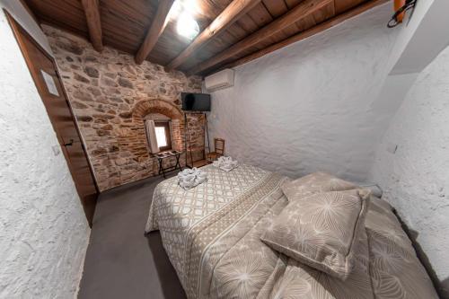 1 dormitorio con cama y pared de piedra en Casa Rural El Palomeque 