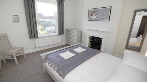 a white bedroom with a bed and a fireplace at Oakland Road, Mumbles in The Mumbles