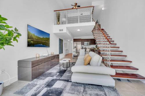 a living room with a staircase and a white couch at Stunning 1 Bedroom Loft in The Heart of Brickell in Miami