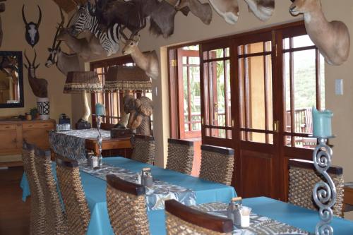a dining room with a blue table and some animals on the wall at Valley Bushveld Country Lodge in Addo