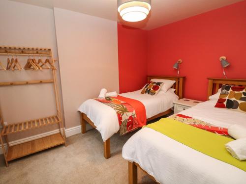 two beds in a room with red walls at 1 Barley Cottages in Matlock