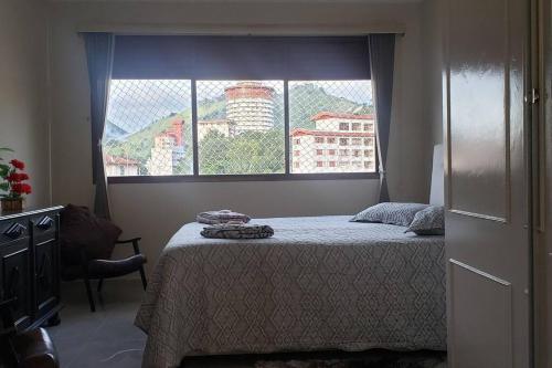 ein Schlafzimmer mit einem Bett und einem großen Fenster in der Unterkunft Apartamento no centro. Tudo novinho, aconchegante in Águas de Lindóia