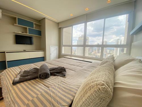 a bedroom with a large bed with towels on it at Flat Studio DNA Smart style in Goiânia