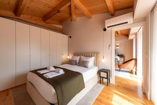 a bedroom with a large bed in a room with wooden ceilings at Ando Living - Flores 200 House in Porto