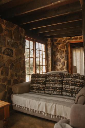 a couch sitting in a room with a stone wall at Wilgeboomsdrift Safaris in Modimolle