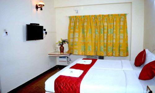 1 dormitorio con cama blanca y cortina amarilla en Vel Residency, en Thanjāvūr