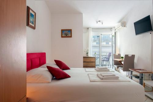 a bedroom with a large white bed with red pillows at Studios Ruža in Baška Voda