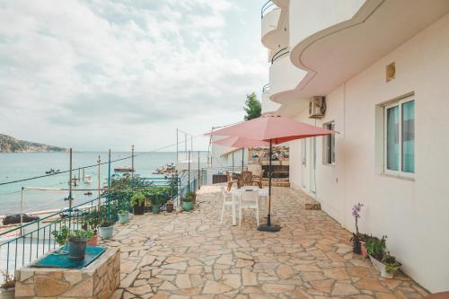 een patio met een parasol en uitzicht op het water bij Rooms by the sea in Himare