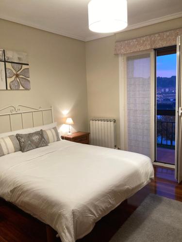 Un dormitorio con una gran cama blanca y una ventana en Ontziola - ONGI ETORRI en Zumaia