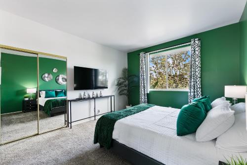 ein grünes Schlafzimmer mit einem Bett und einem Fenster in der Unterkunft Beverly Hills Glamour Oasis 2 BR Apt with Parking 304 in Los Angeles