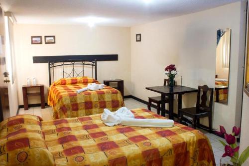 喬盧拉的住宿－Villas Hotel Cholula，酒店客房设有两张床和一张桌子。