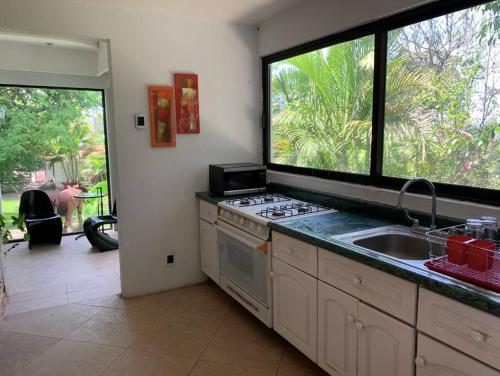 a kitchen with a stove and a sink and a window at Brisas el Valle in Temixco