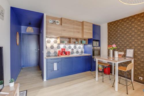 eine Küche mit blauen Wänden und einem Tisch mit Stühlen in der Unterkunft Gîte des randonneurs de la Presqu'île de Lézardrieux Bretagne in Lézardrieux